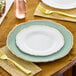 A Visions white plastic plate with a gold vintage rim on a table with a gold fork.