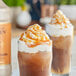 Two drinks with caramel sauce and whipped cream on top.