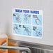 A white and blue "Wash Your Hands" safety decal on the wall.