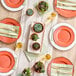 A table setting with Visions Terra Cotta plastic plates with gold rims and utensils, next to potted plants.