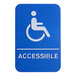 A white sign with a blue person in a wheelchair symbol and the word "Accessible" in blue.