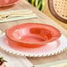 A table setting with a pink plate and a Visions gold rimmed bowl.