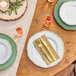 A table setting with white plates with gold trim, forks and knives.