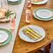 A table set with white plastic bowls with gold vintage rims, plates, and gold cutlery.