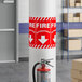 A red and white Lavex safety label for a fire extinguisher with a down arrow.