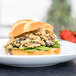 A sandwich on a plate with Barvecue plant-based shredded chicken, spinach, and strawberries.