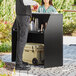 A man and woman standing next to a Lancaster Table and Seating foldaway bar with a black laminate finish.