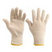 A close-up of a pair of white cotton work gloves with yellow tips.