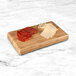 A rectangular faux bamboo display riser with slices of meat and cheese on a counter.