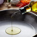 A person pouring Del Destino olive oil into a pan of vegetables.