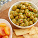 A bowl of green stuffed Manzanilla olives next to a bowl of crackers on a table.