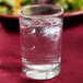 An Anchor Hocking Regency heavy base drinking glass filled with water and ice on a table.