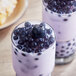 A glass of milk with Possmei blueberry popping boba on top.