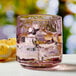 An Anchor Hocking rosewater pink rocks glass filled with water, ice, and a lemon slice.