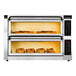 A PizzaMaster electric double countertop pizza oven with two trays of food inside.