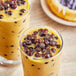 A glass of milk with brown Possmei Tapioca Boba Pearls on top.