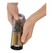 A person's hands holding a glass container with a copper Cilio salt/pepper mill.