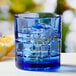 An Anchor Hocking Coastal Blue rocks glass with ice and a lemon slice.