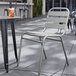 A Lancaster Table & Seating silver steel side chair on a patio.