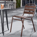 A Lancaster Table & Seating bronze powder-coated steel outdoor side chair on a patio.