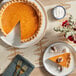 A Southern Roots vegan pumpkin pie on a plate with a fork and a slice missing.