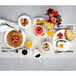 A Tuxton Monterey ivory china plate with a berry band holding waffles with strawberries on top on a breakfast table.