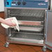 A person using a towel to open an Alto-Shaam Undercounter Cook and Hold Oven.