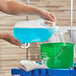 A person pouring a jug of blue liquid into a bucket.