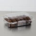 A clear Dart plastic container of chocolate cookies on a bakery counter.