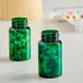 Two green PET packer bottles with green pills inside.