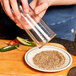 A person pouring Demitri's Bacon Rim Shot salt into a plate.