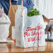 A person using a Source Direct plastic bag to hold a bunch of greens.