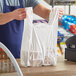 A person holding a Source Direct Inc. plastic t-shirt bag in front of a cash register.