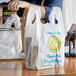 A man using a white heavy-duty plastic Source Direct Inc. T-shirt bag to hold groceries.