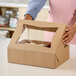 A woman opening a brown Southern Champion cake box with a clear window.