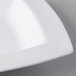 A close up of a Libbey white rectangular porcelain bowl with curved edges.