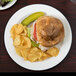 A Libbey medium rim porcelain plate with a sandwich and potato chips on it.