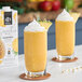 Two glasses of pineapple smoothie with whipped cream and pineapple slices.