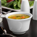 A Libbey Royal Rideau white porcelain bouillon with soup on a table.