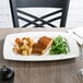 A Libbey rectangular white porcelain plate with a piece of salmon and potatoes on a table.