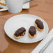 A Libbey white porcelain saucer with chocolate covered pastries on it.