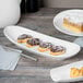 A table with a Libbey white porcelain plate of pastries and a fork.