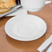 A hand holding a Libbey white porcelain tea cup over a white saucer.