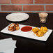 A Libbey white porcelain tray with 3 wells of food and a drink on a table.