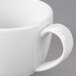 A close-up of a Libbey white espresso cup filled with a white liquid.