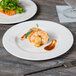 A Libbey white porcelain plate with food on a table.