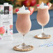 Two glasses of wildberry smoothie with whipped cream and berries on a white background.