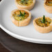 A Libbey white porcelain tray with small quiches and herbs on it.