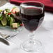 A Libbey Gibraltar goblet of red wine next to a salad on a white table