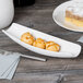 A white Libbey canoe plate with food on it on a table.